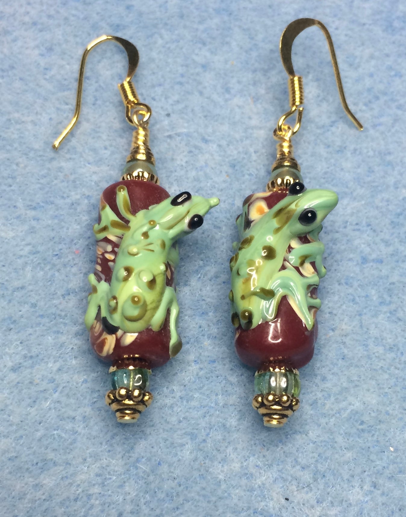 Dark red and green lamp work lizard bead earrings adorned with green Czech glass beads.