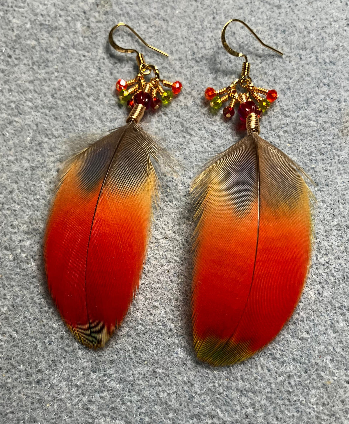 Red and green scarlet macaw feather earrings adorned with red Chinese crystal beads and tiny dangling red and green Chinese crystal beads.