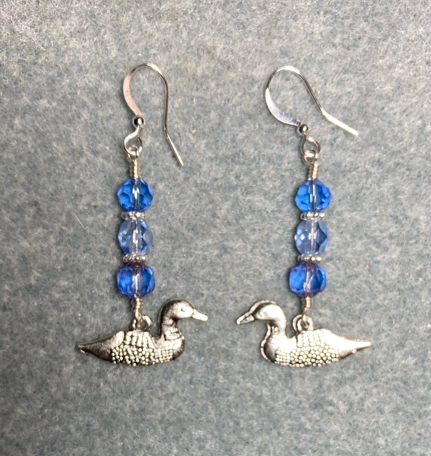 Silver mallard duck (loon) charm earrings adorned with light blue Czech glass beads.