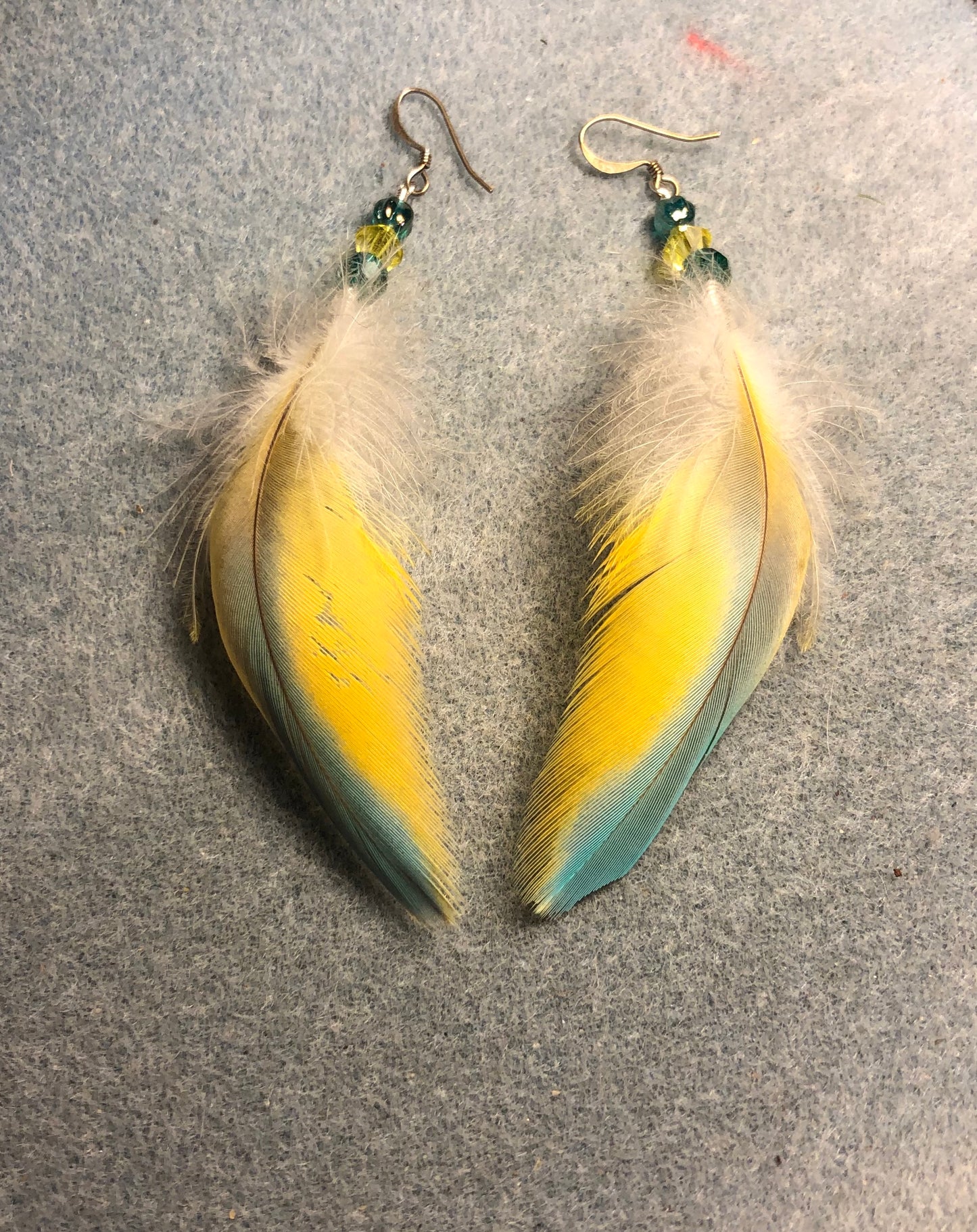 Blue and yellow macaw feather earrings adorned with blue and yellow Czech glass beads.