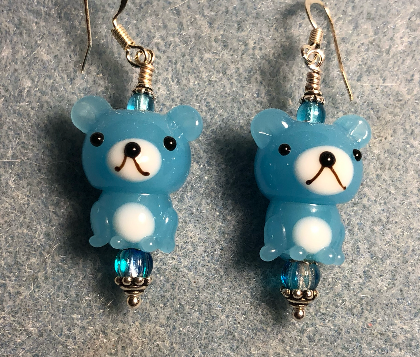Opaque turquoise and white lamp work teddy bear bead earrings adorned with turquoise Czech glass beads.
