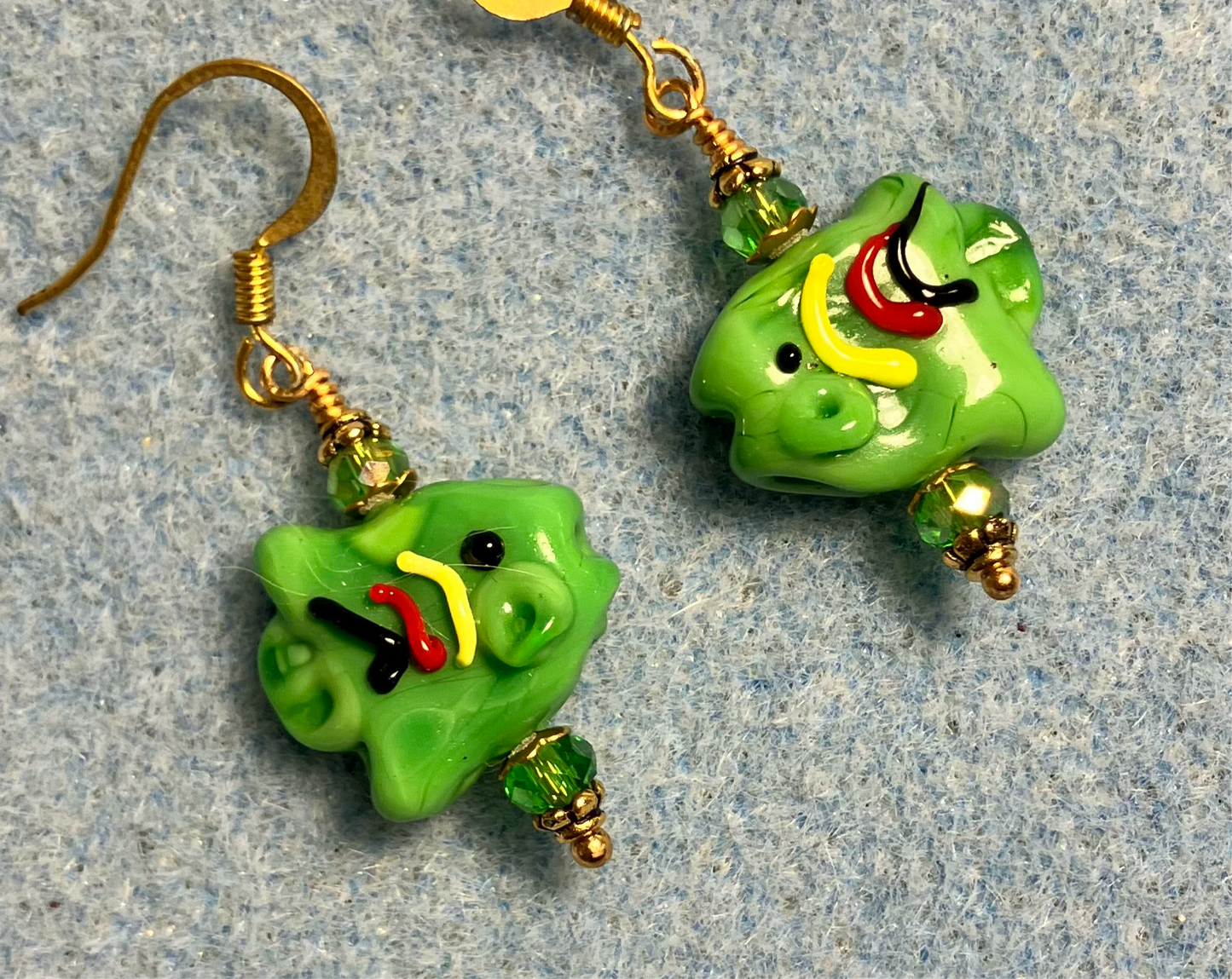 Opaque green lamp work fish bead earrings adorned with green Chinese crystal beads.
