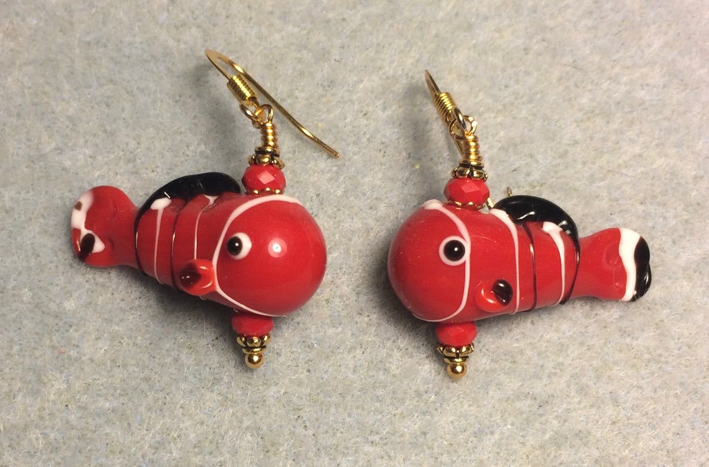 Red, black, and white lamp work fish bead earrings adorned with red Chinese crystal beads.