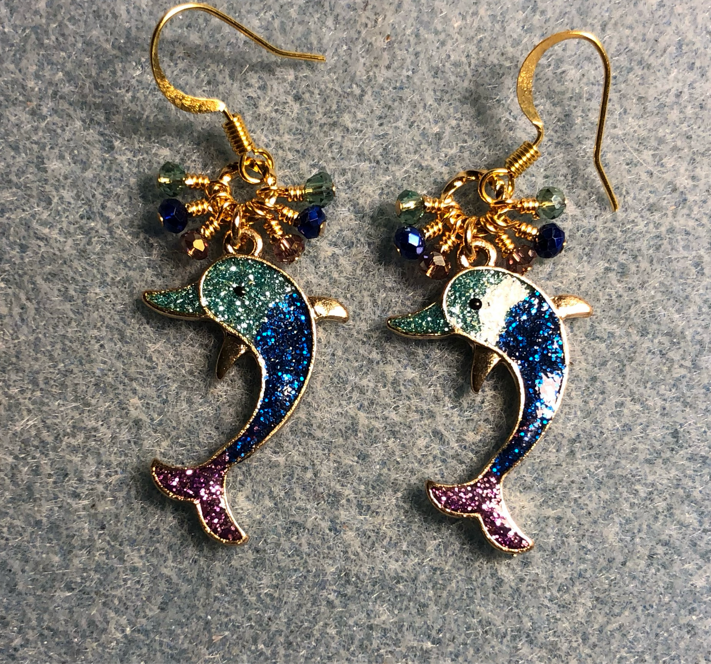 Aqua, blue, and violet glittery resin dolphin charm earrings adorned with tiny dangling aqua, blue, and violet Chinese crystal beads.