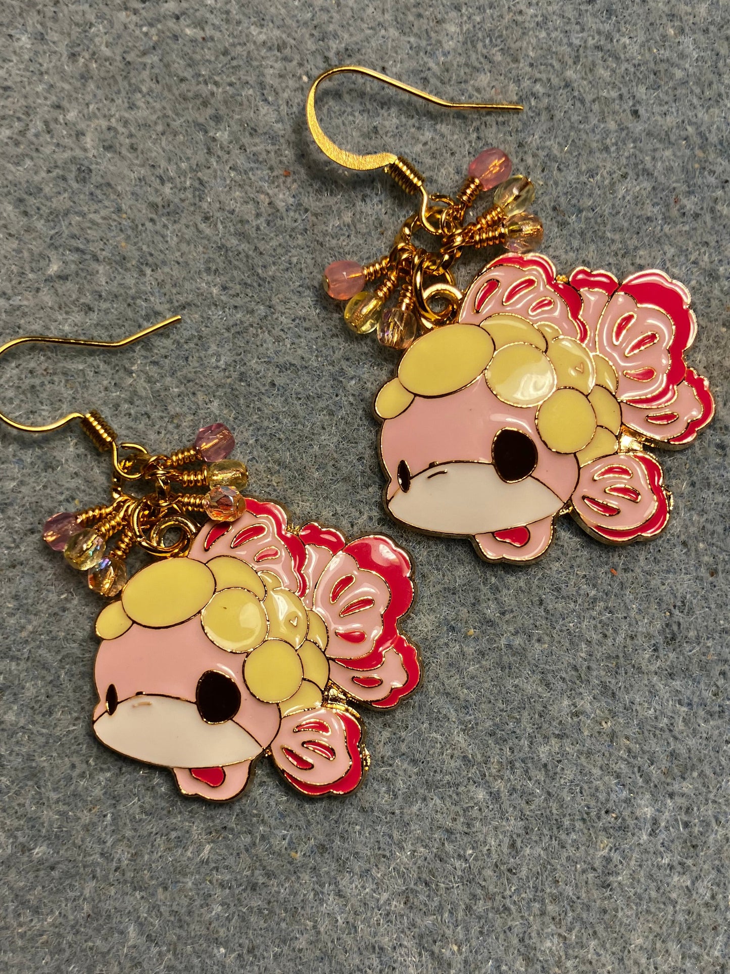 Large pink, yellow, and black enamel fish charm earrings adorned with small dangling pink and yellow Czech glass beads.