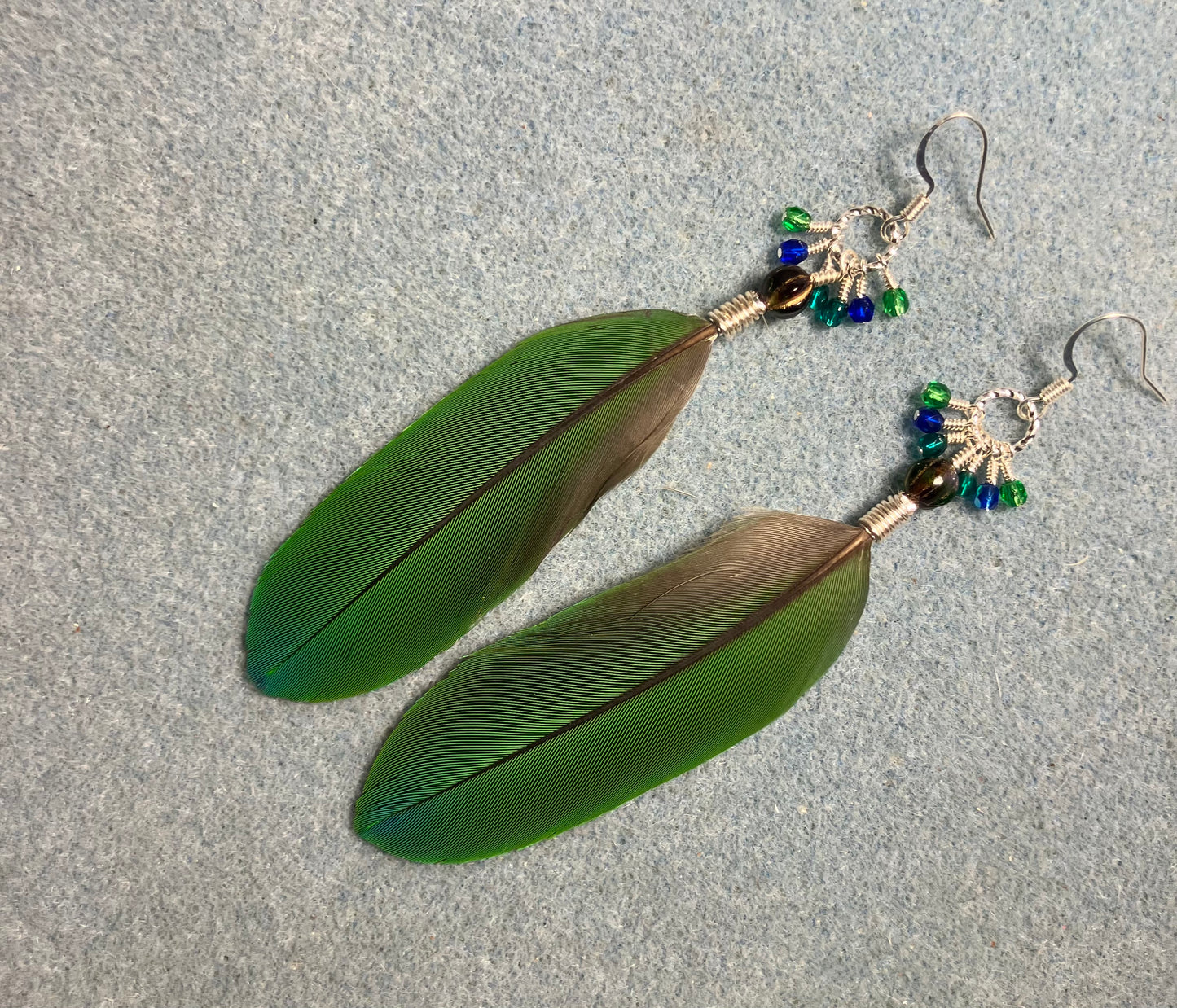 Blue and green blue headed Pionus feather earrings adorned with blue green beads and tiny dangling blue and green Czech glass beads.