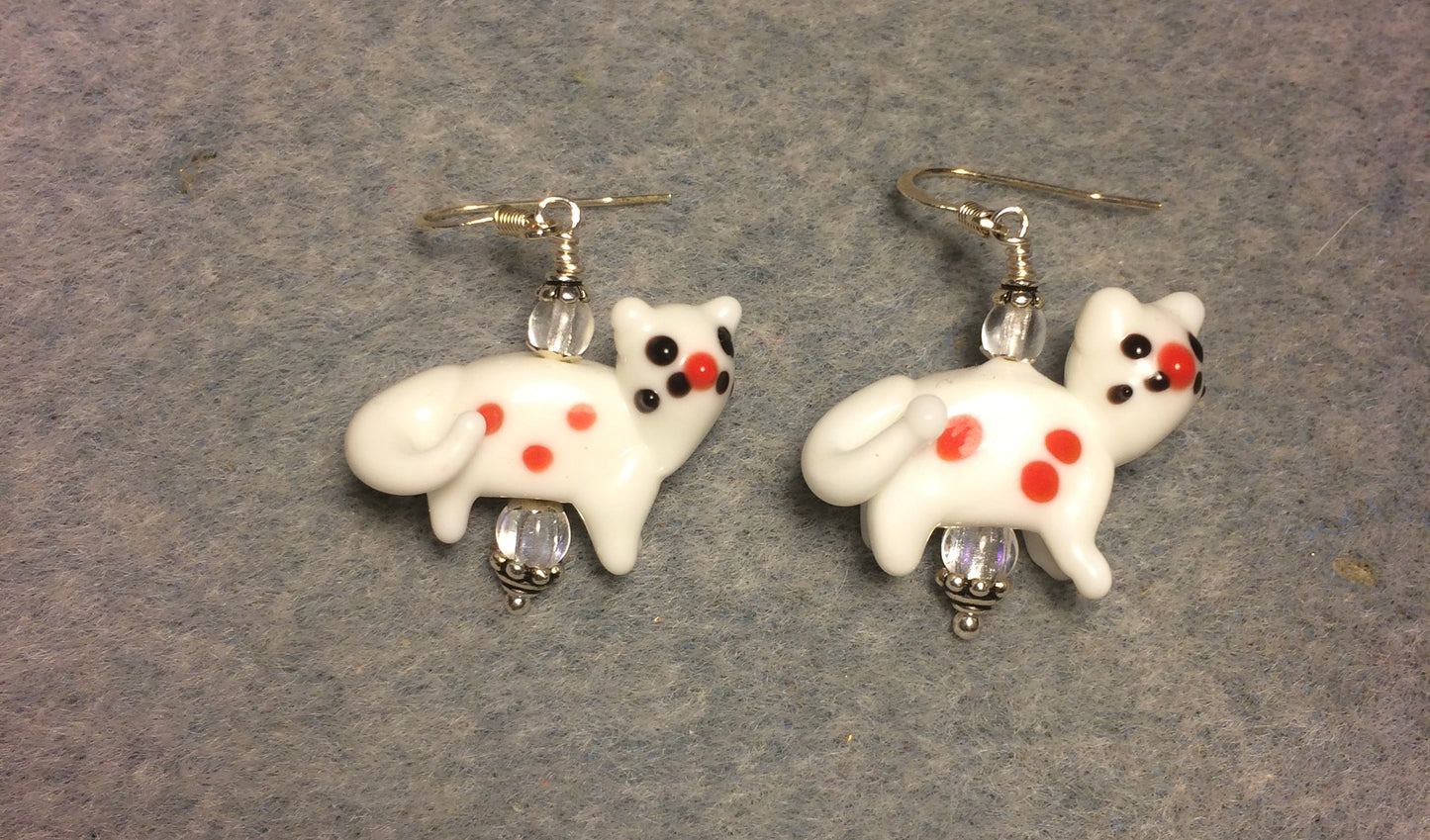 Opaque white lamp work spotted cat bead earrings adorned with clear Czech glass beads.