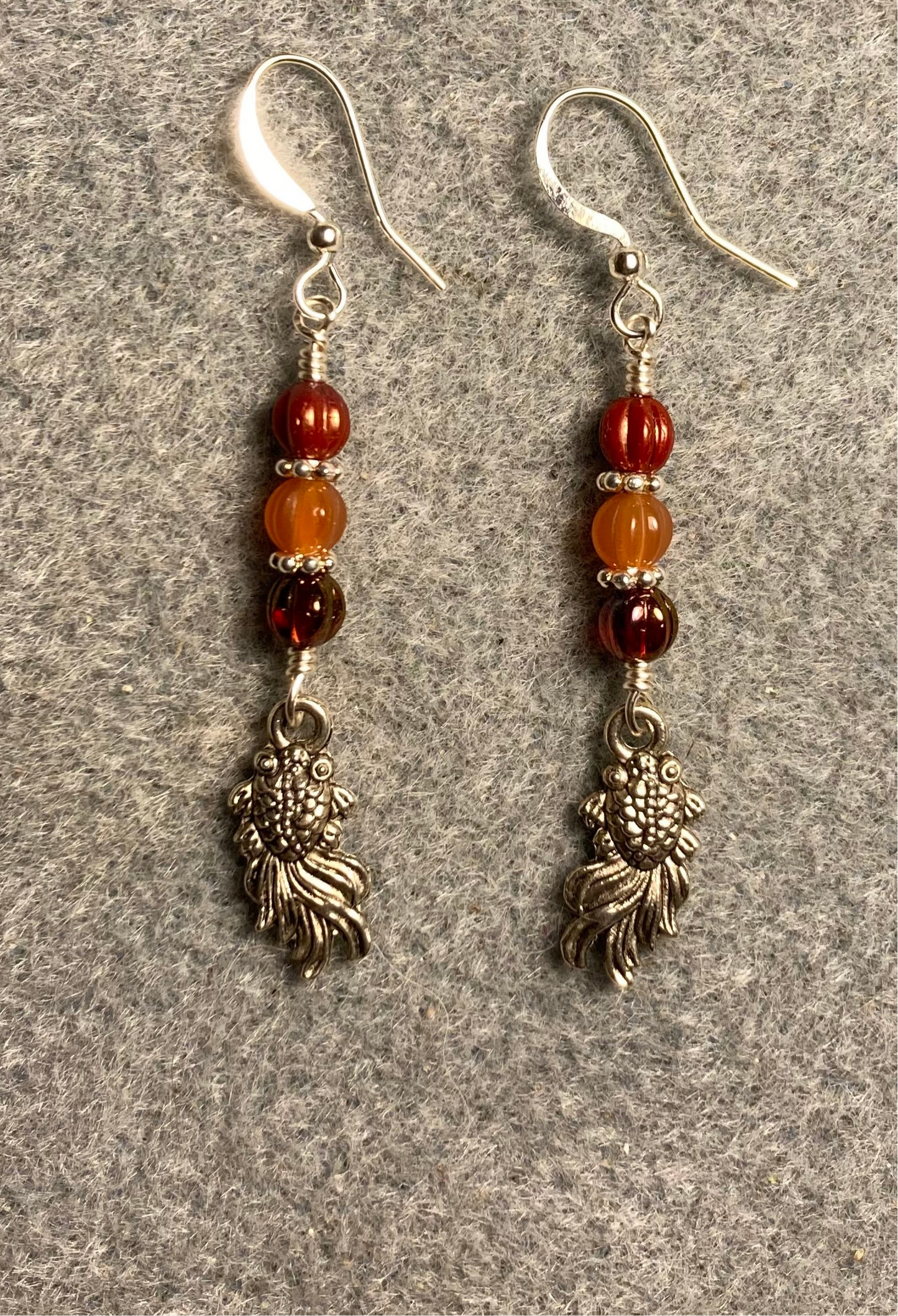Small silver goldfish charm earrings adorned with small orange Czech glass melon beads.
