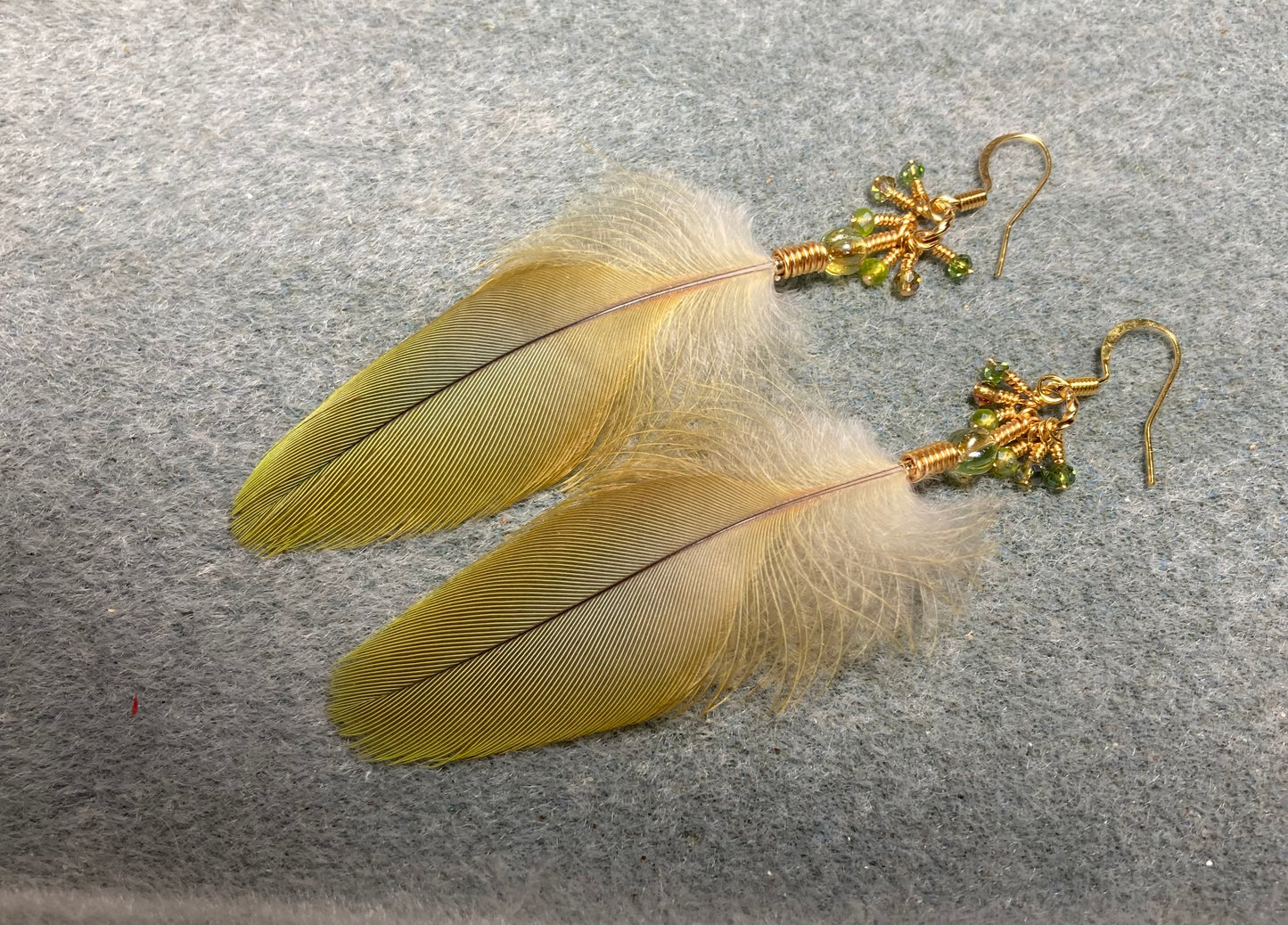 Olive green red fronted macaw feather earrings adorned with olive green Czech glass beads and tiny dangling olive green Chinese crystal beads.