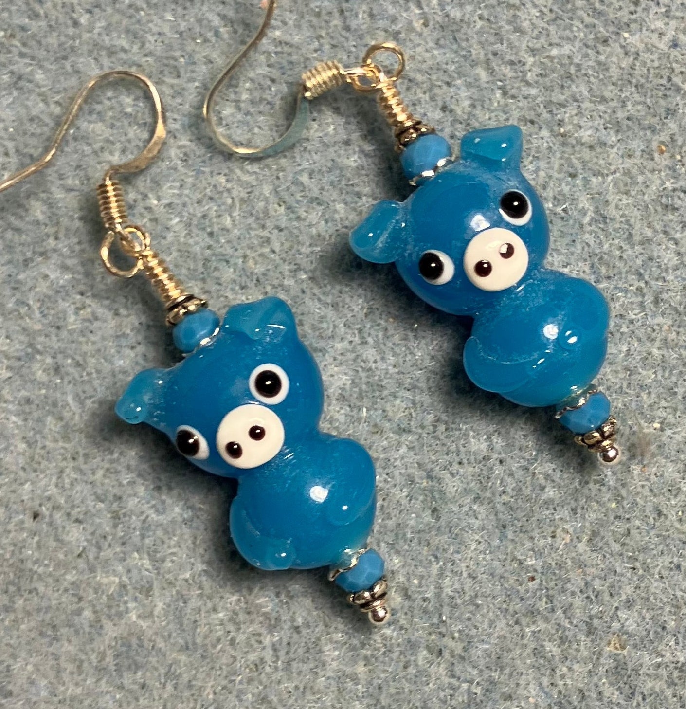 Blue lamp work standing pig bead earrings adorned with blue Chinese crystal beads.