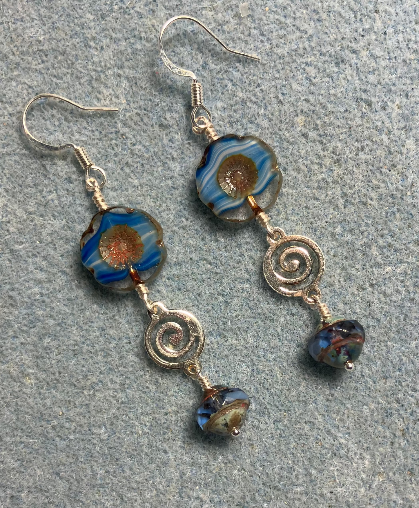 Blue striped Czech glass pansy bead earrings adorned with silver swirly connectors and blue Czech glass Saturn beads.