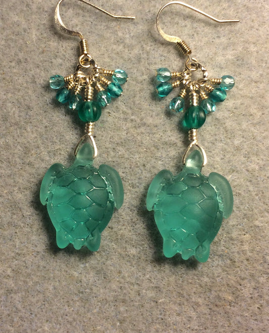 Translucent light teal sea glass sea turtle bead earrings adorned with teal Czech glass beads and small dangling light teal Czech glass beads.