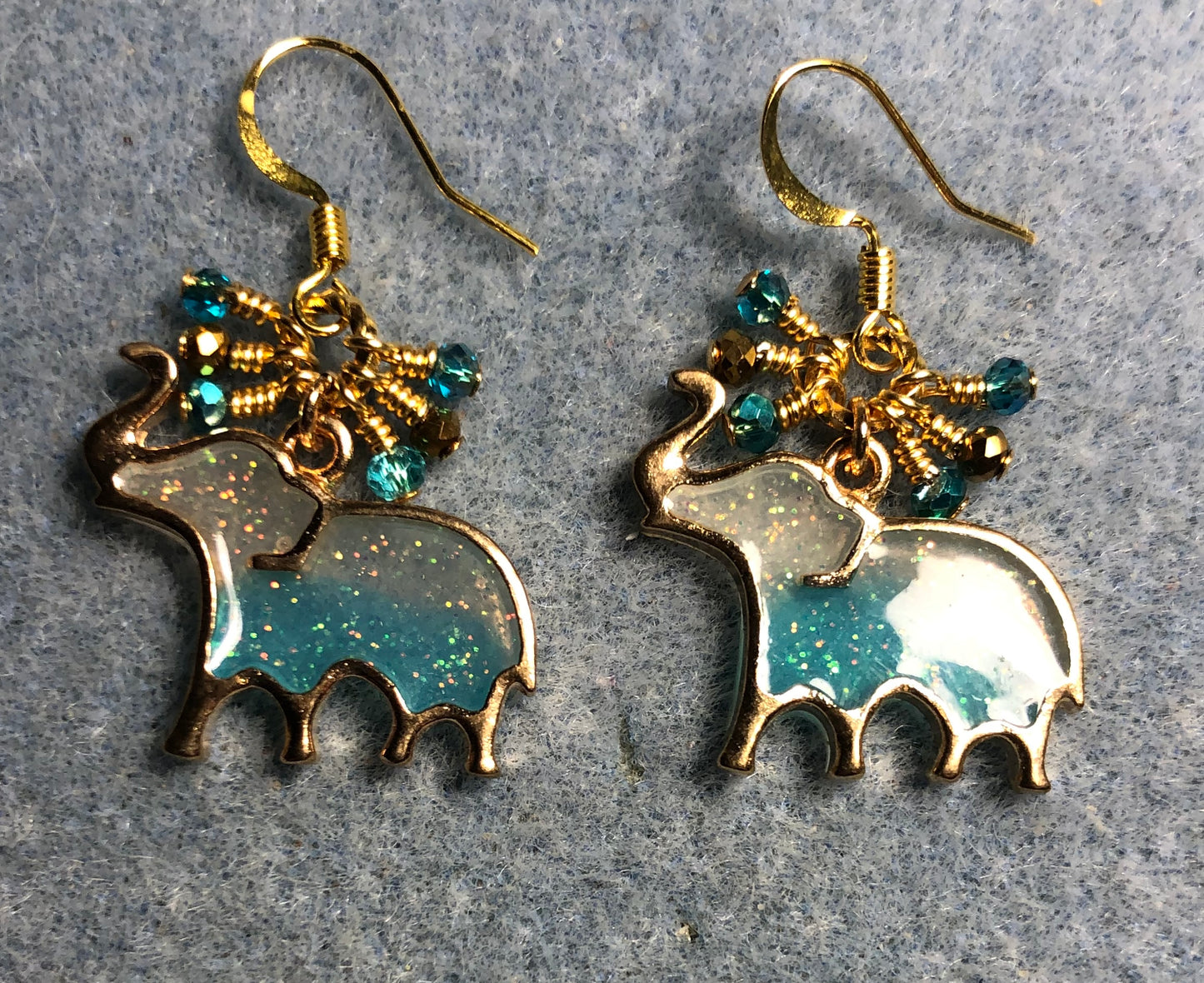 Turquoise and gold sparkly resin elephant charm earrings adorned with tiny dangling turquoise and gold Chinese crystal beads.