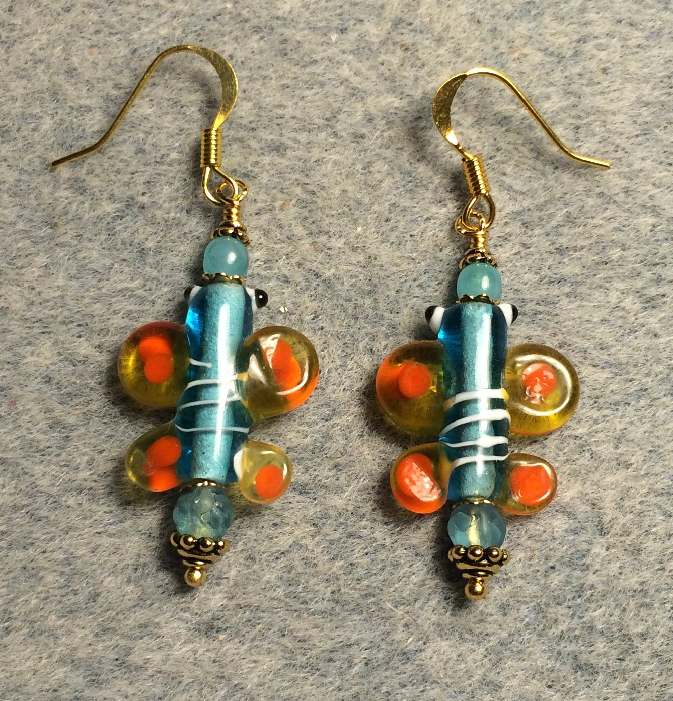 Light turquoise and orange lamp work butterfly bead earrings adorned with light turquoise Czech glass beads.