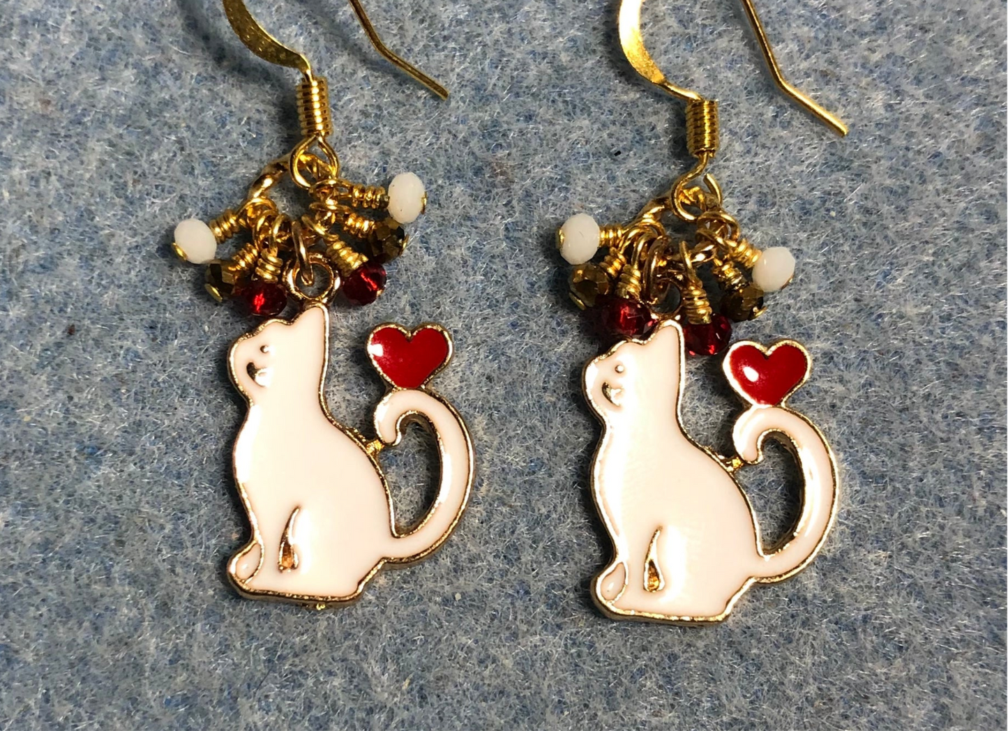 White and red enamel cat charm earrings adorned with tiny dangling white, gold, and red Chinese crystal beads.