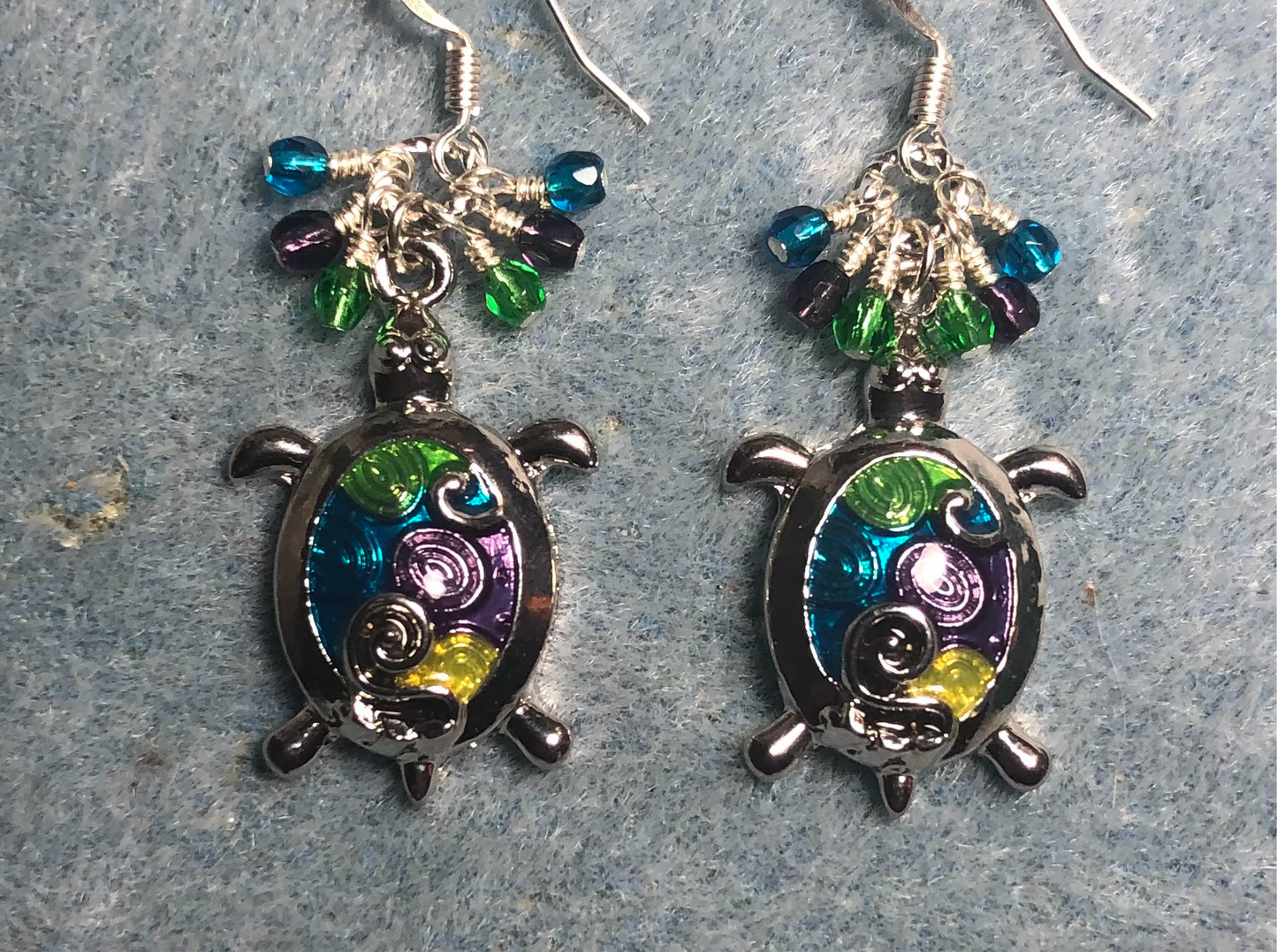 Green, purple, and turquoise enamel turtle charm earrings adorned with small dangling green, purple, and turquoise Czech glass beads.