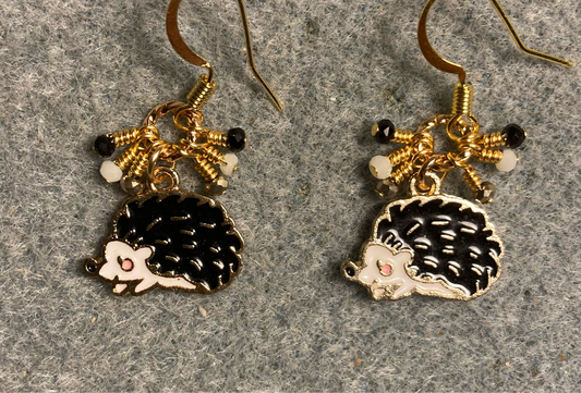 Black and white enamel hedgehog charm earrings adorned with tiny dangling black, white, and and gold Chinese crystal beads.