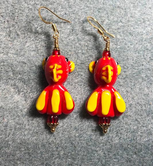 Red and yellow lamp work striped fish bead earrings adorned with red Czech glass beads.