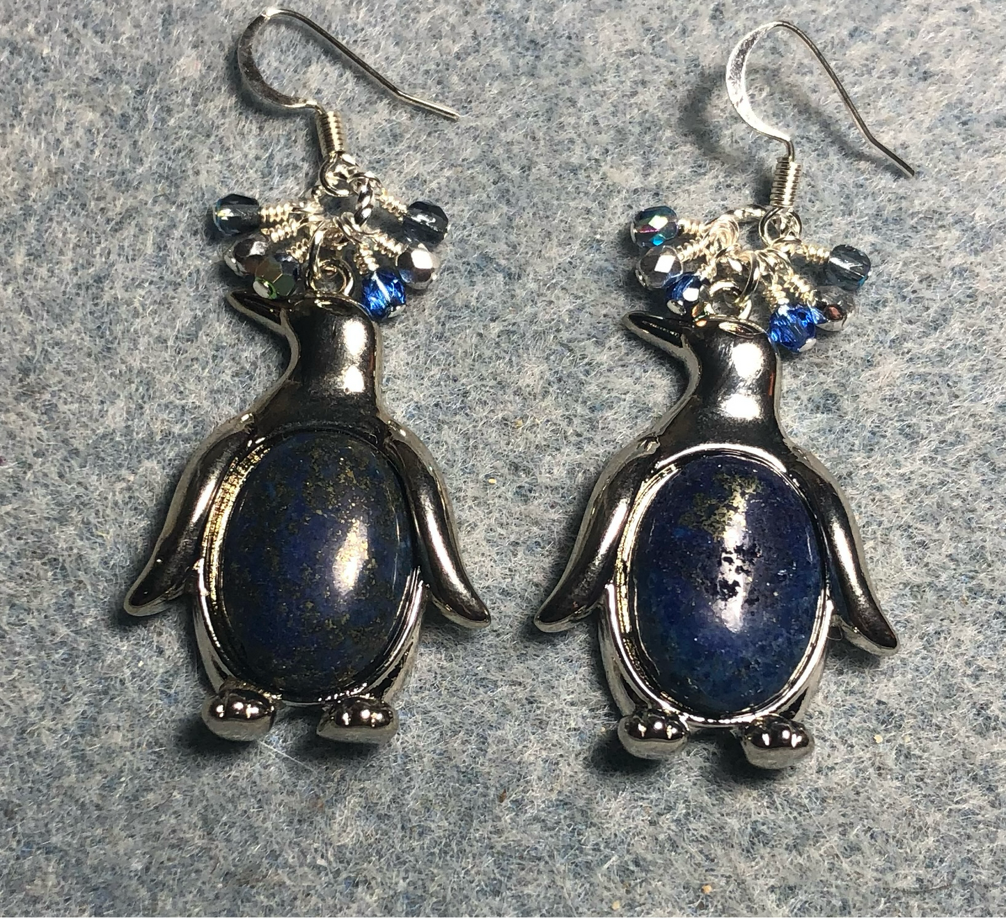 Large silver and blue lapis lazuli gemstone penguin charm earrings adorned with small dangling blue and silver Czech glass beads.