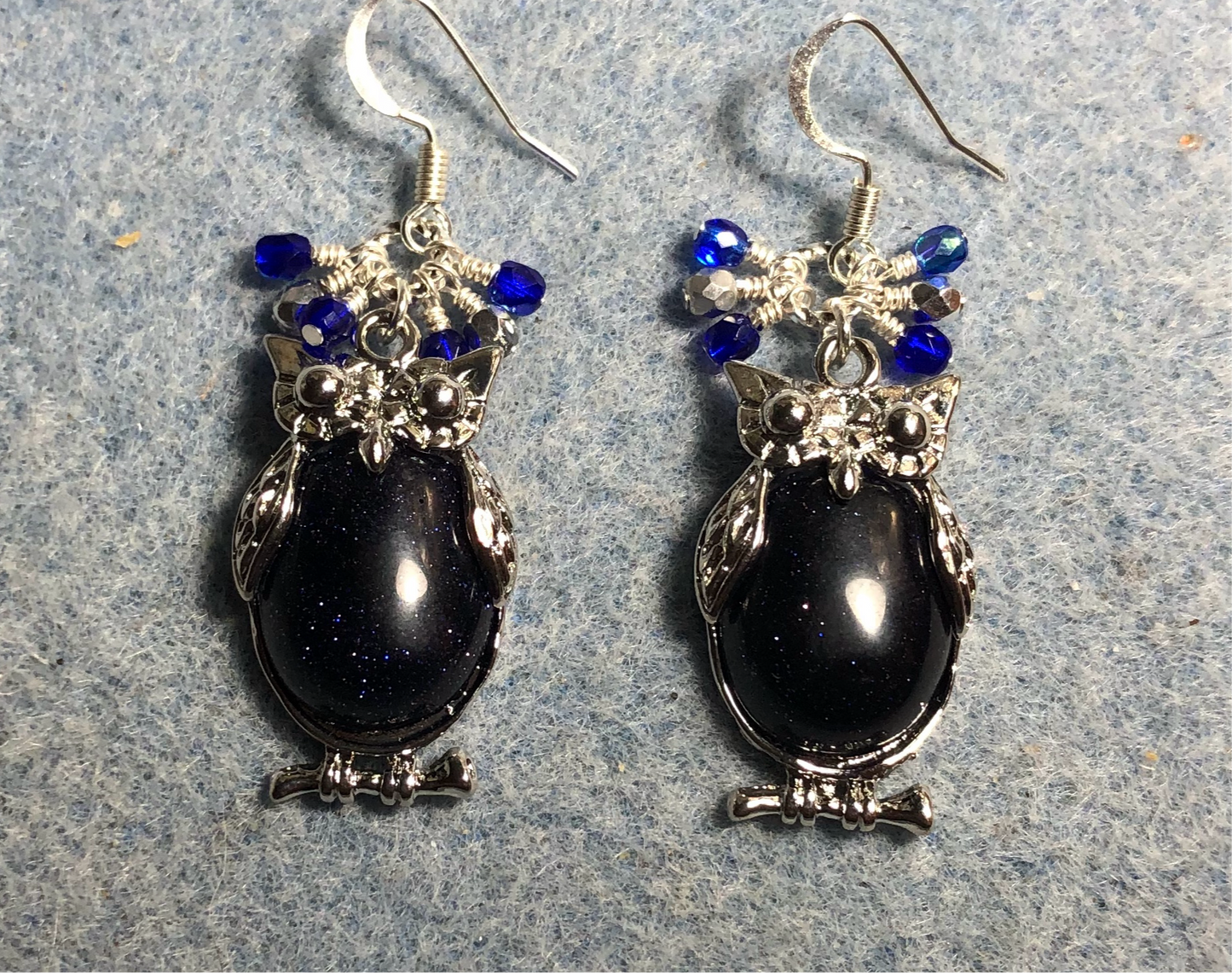 Large silver and blue goldstone gemstone owl charm earrings adorned with small dangling dark blue and silver Czech glass beads.