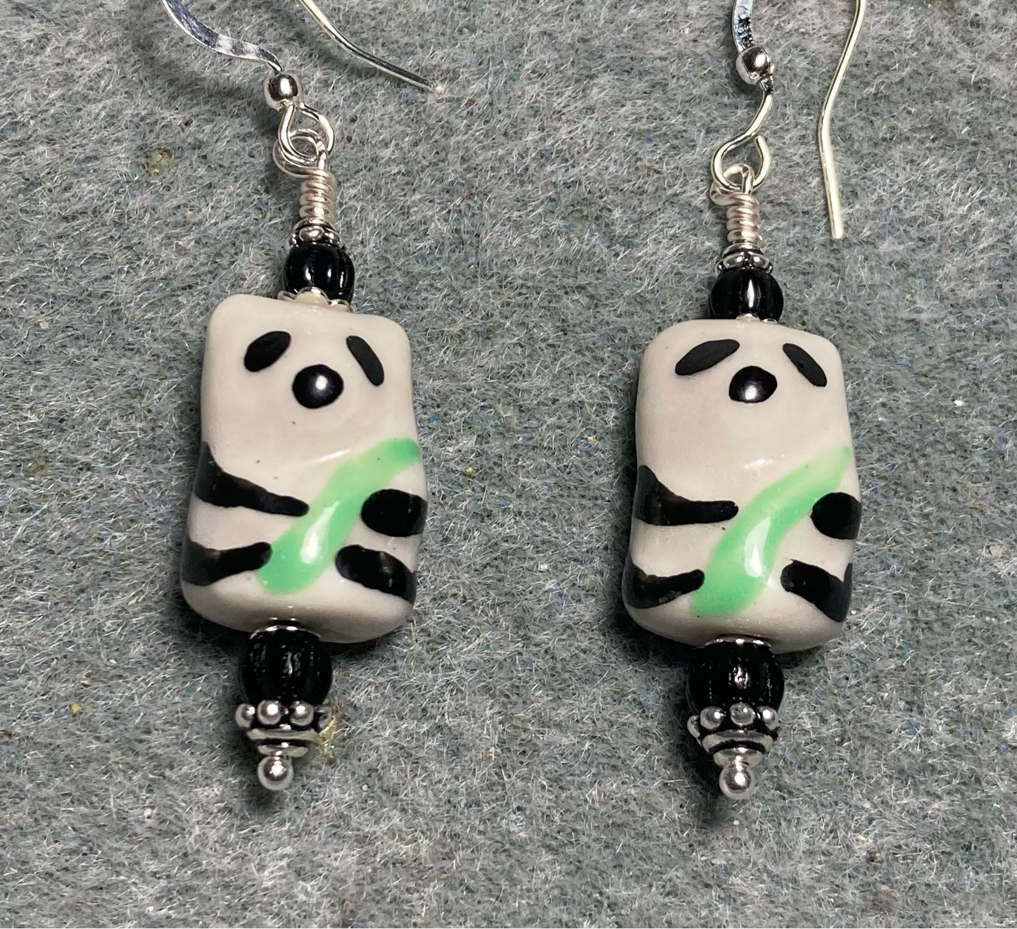 Black, white, and green ceramic panda bear bead earrings adorned with black Czech glass beads.