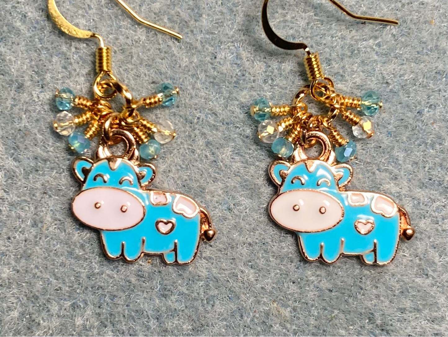 Turquoise and white enamel cow charm earrings adorned with tiny dangling turquoise and clear Chinese crystal beads.