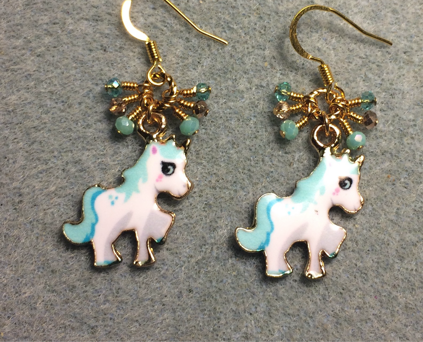 Small turquoise, white, and gold enamel unicorn charm earrings adorned with tiny dangling turquoise and gold Chinese crystal beads.