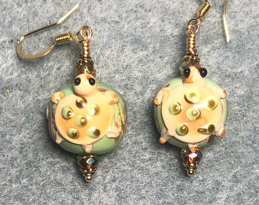 Light green and tan lamp work turtle bead earrings adorned with sparkly green Chinese crystal beads.