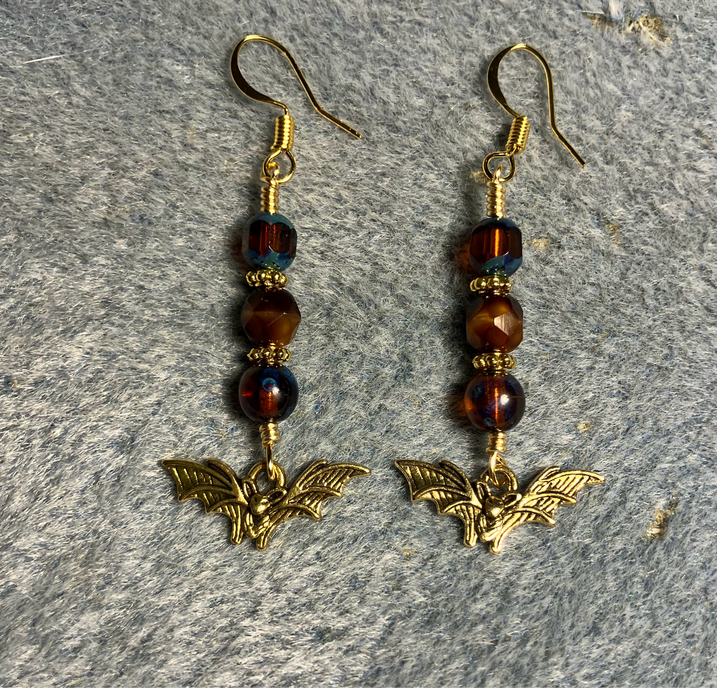 Small gold flying bat charm earrings adorned with brown Czech glass beads