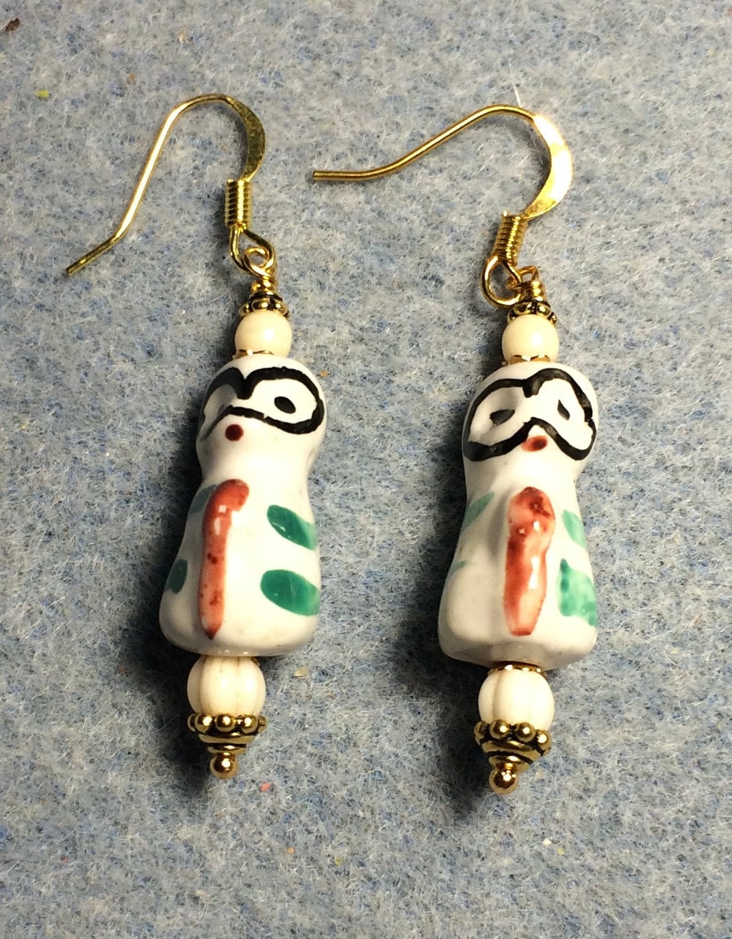 Off white, orange, green, and black ceramic lemur bead earrings adorned with off white Czech glass beads.