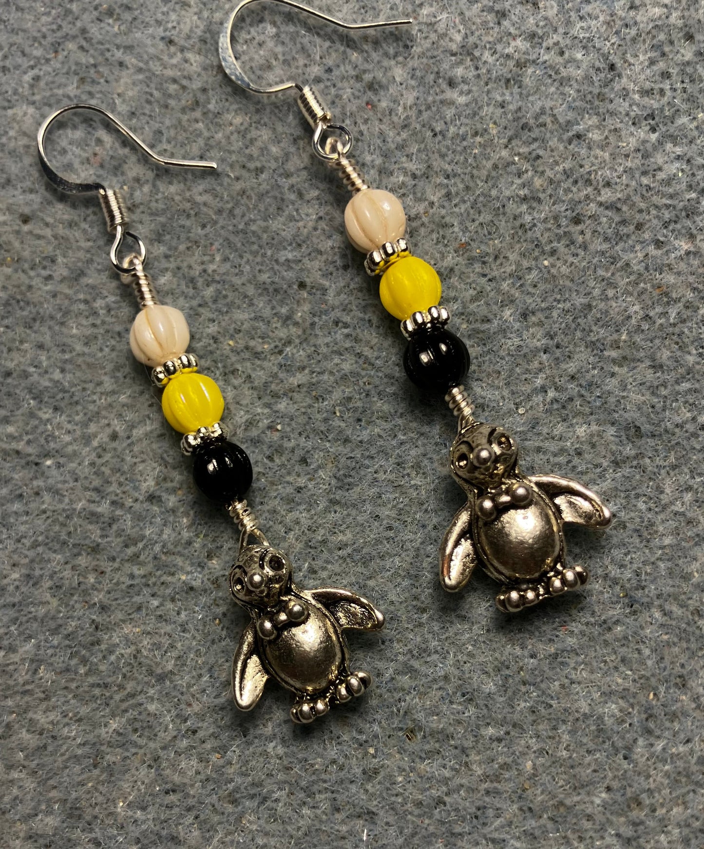 Small silver silly penguin charm earrings adorned with small black, yellow, and white Czech glass melon beads