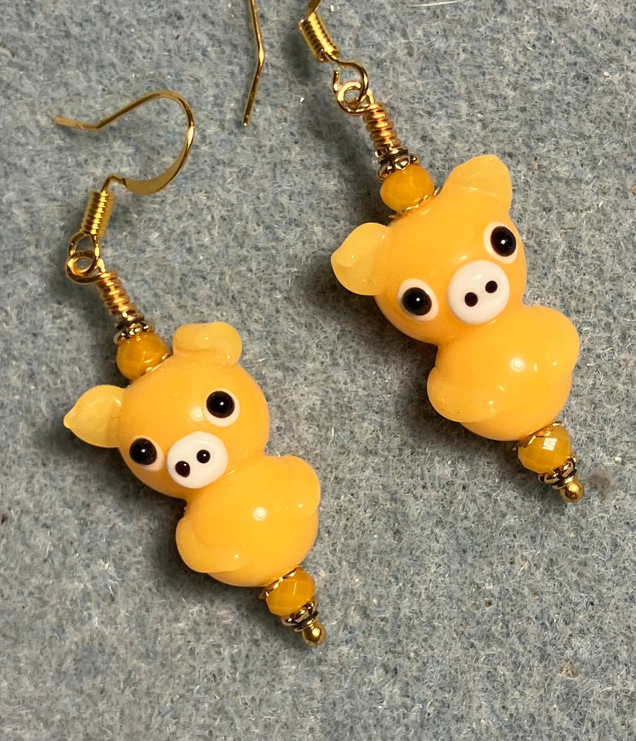 Amber yellow lamp work standing pig bead earrings adorned with amber yellow Chinese crystal beads.
