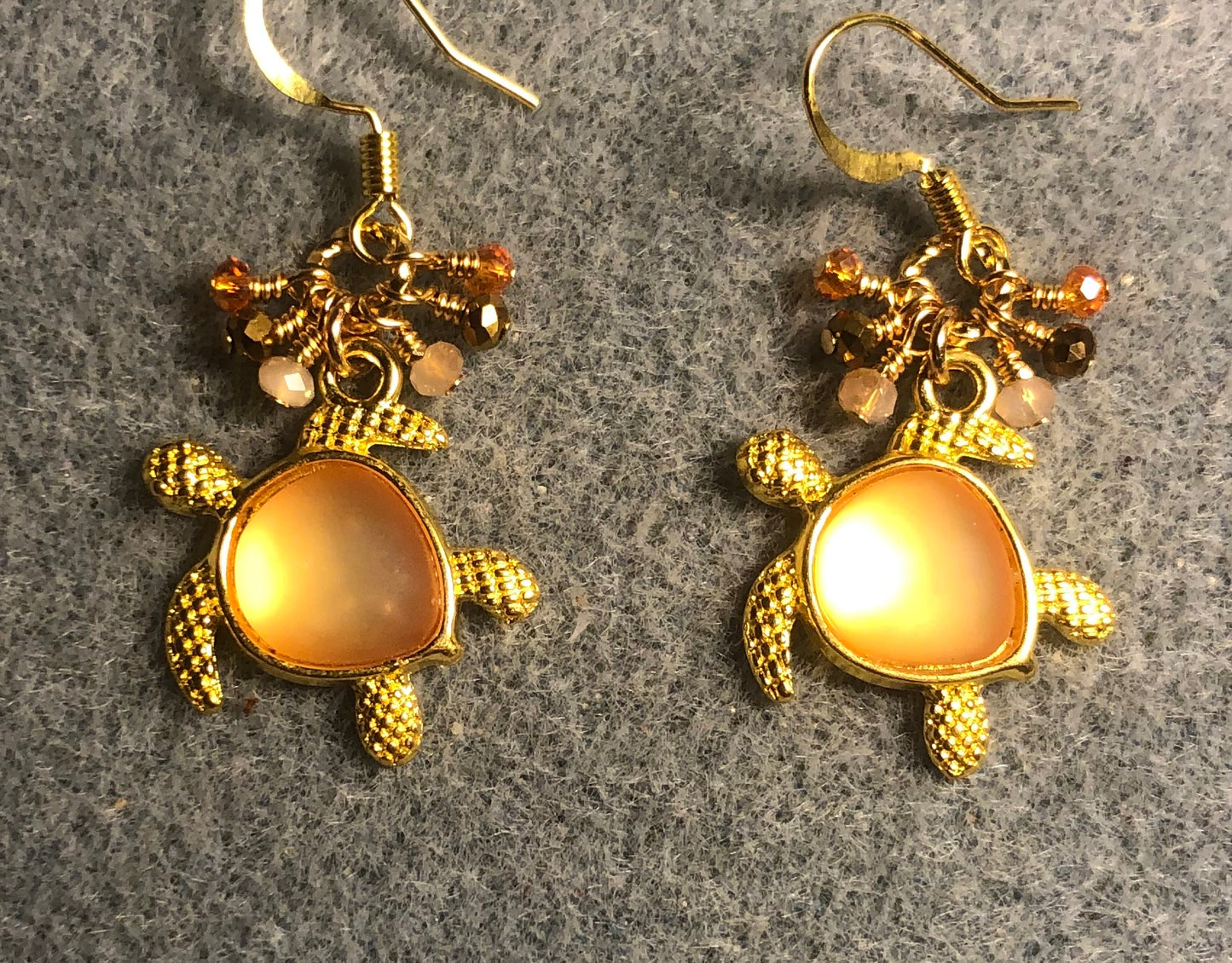 Gold and orange fiber optic sea turtle charm earrings adorned with tiny dangling peach, orange, and gold Chinese crystal beads.