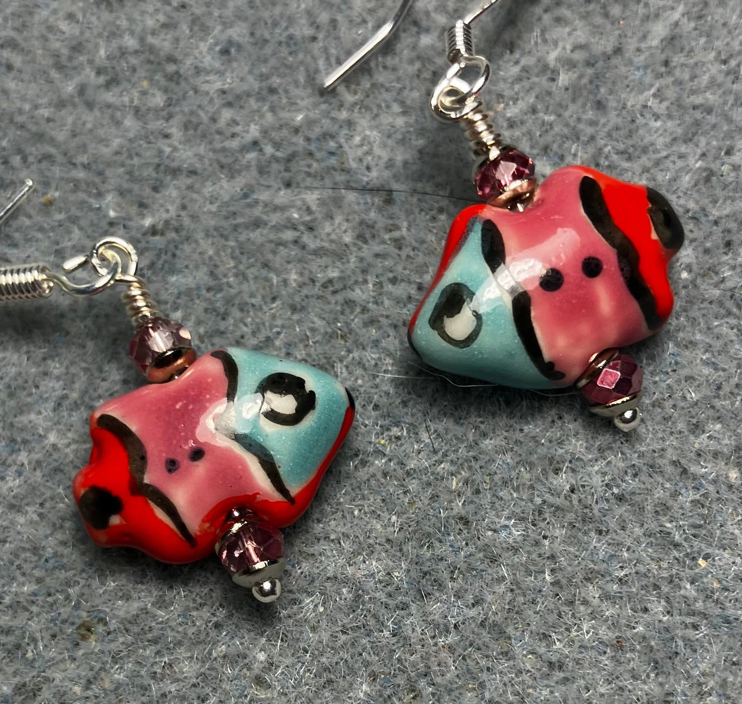 Small pink, red, and turquoise ceramic fish bead earrings adorned with sparkly pink Chinese crystal beads.