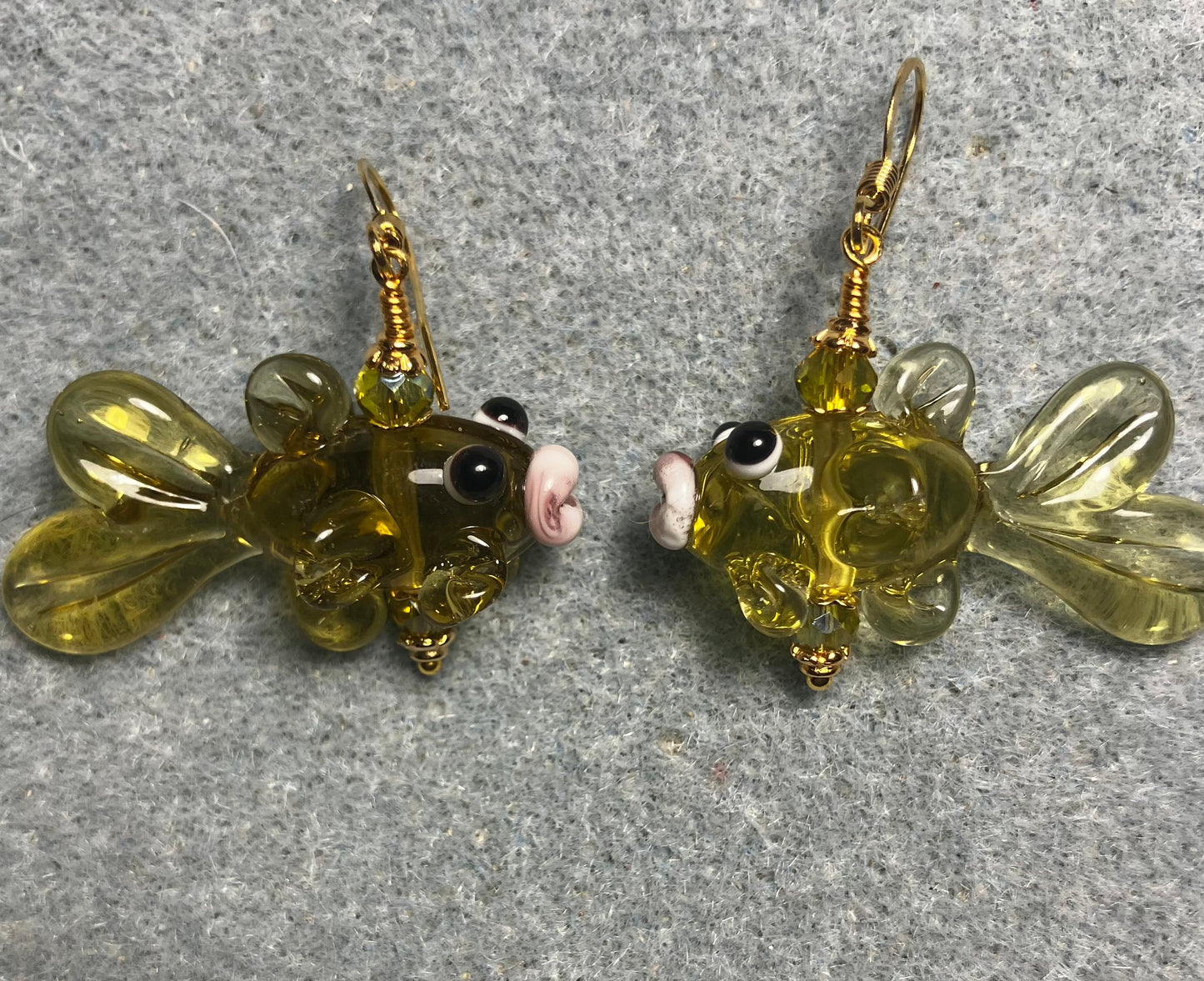 Translucent olive green lamp work fish bead earrings adorned with olive green Chinese crystal beads.