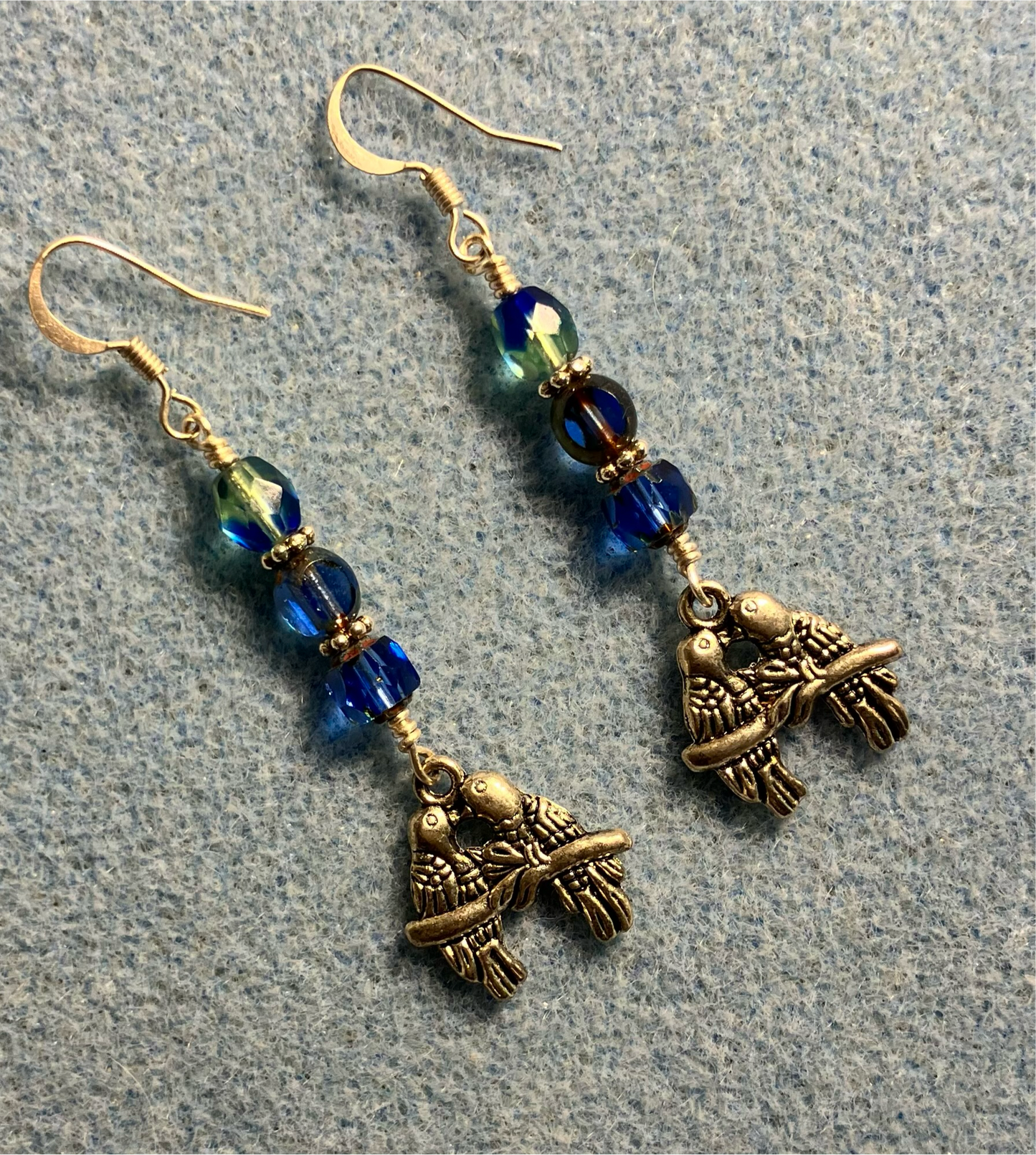 Silver lovebird charm earrings adorned with blue and blue green Czech glass beads.