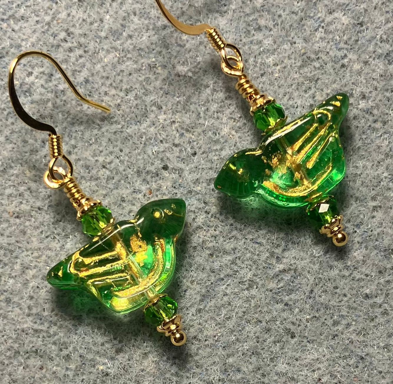 Translucent green (with gold wash) Czech glass bird bead earrings adorned with green Chinese crystal beads.