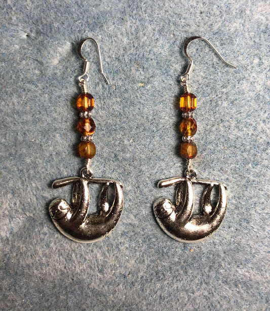Silver hanging sloth charm earrings adorned with amber Czech glass beads.