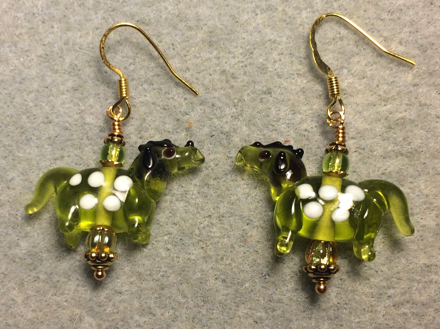 Translucent olive green and white lamp work spotted horse bead earrings adorned with olive green Czech glass beads.