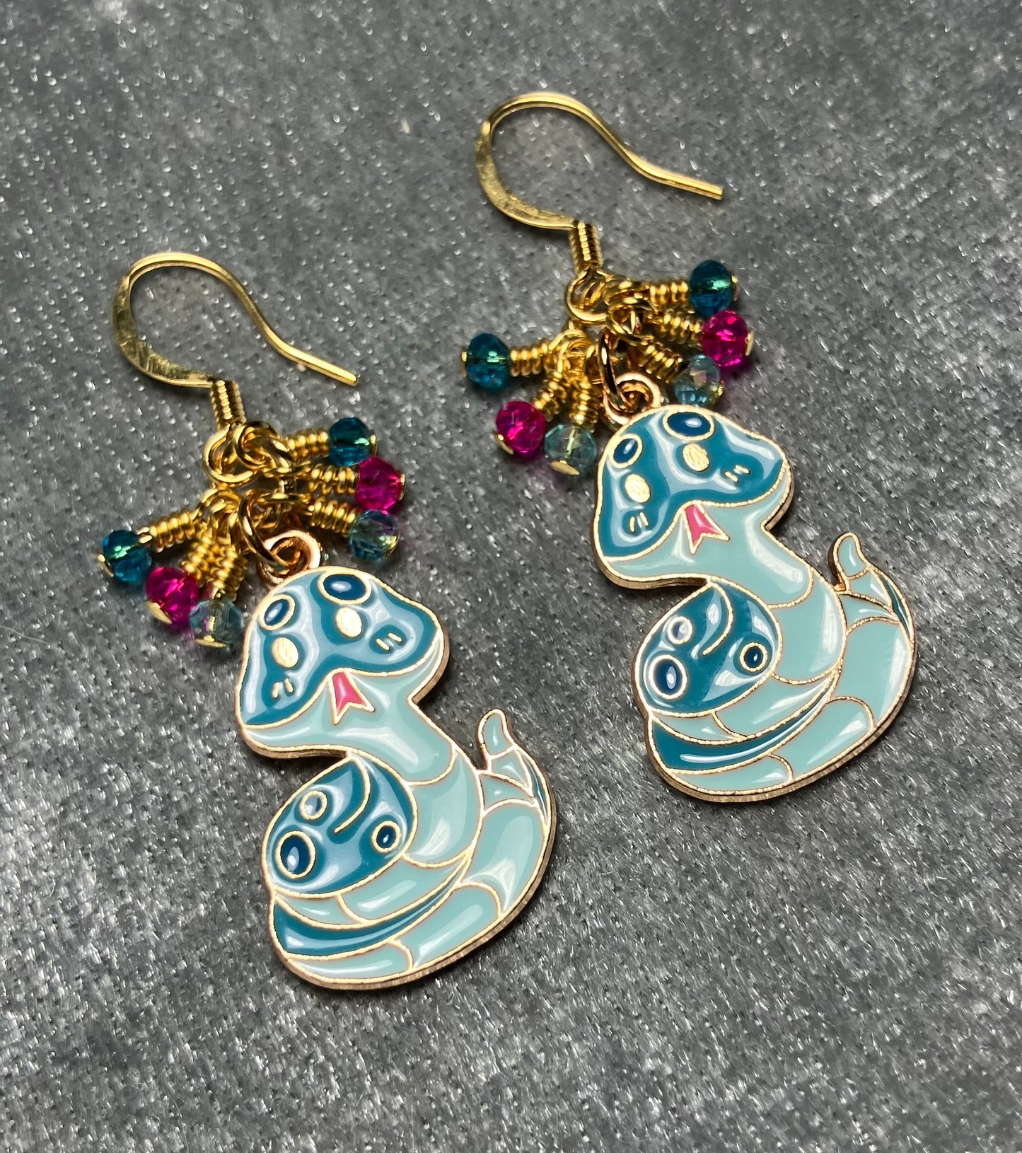 Turquoise and pink enamel snake charm earrings adorned with tiny dangling dark turquoise, hot pink, and light turquoise Chinese crystal beads.