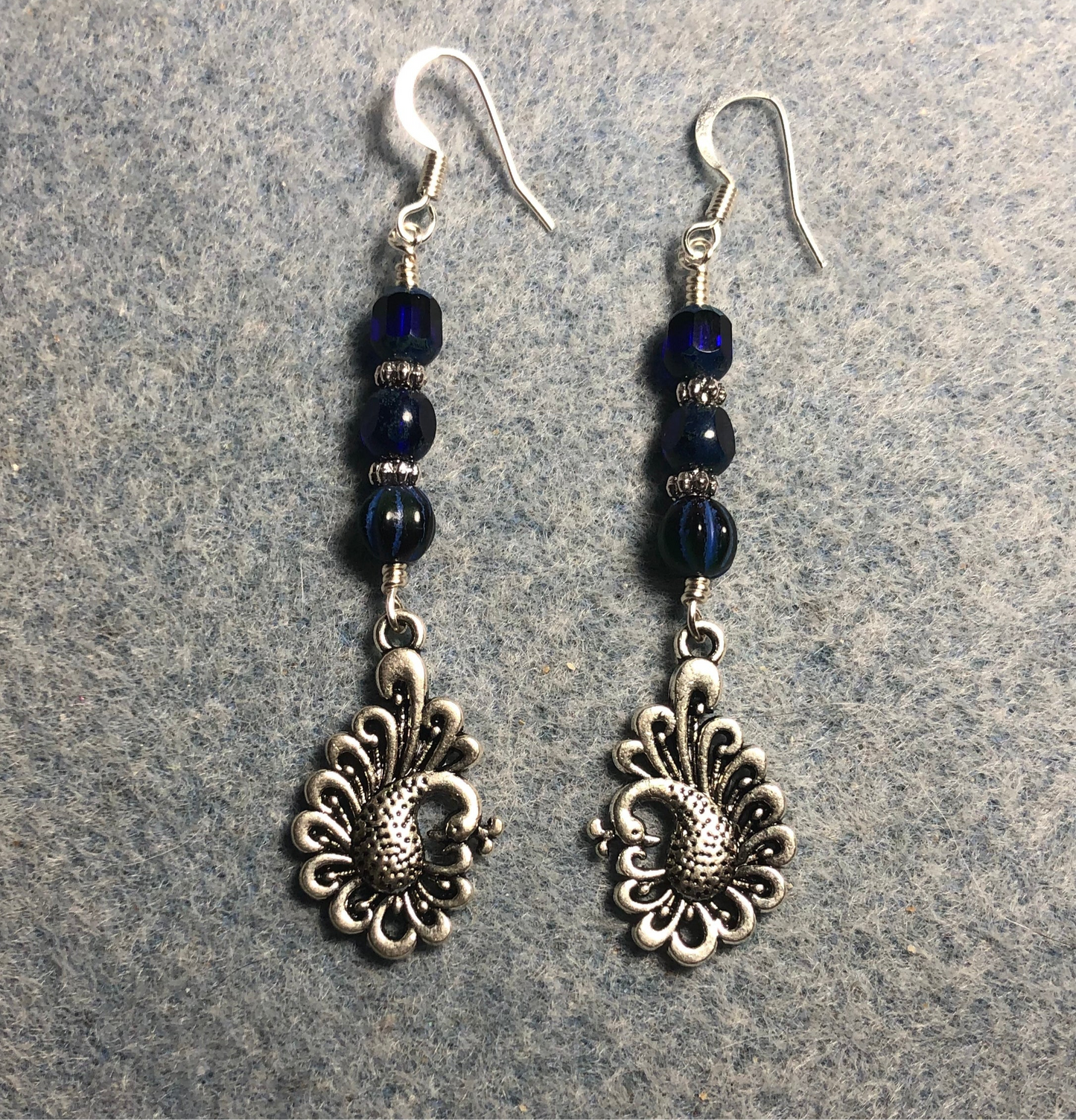 Silver peacock charm earrings adorned with dark blue Czech glass beads