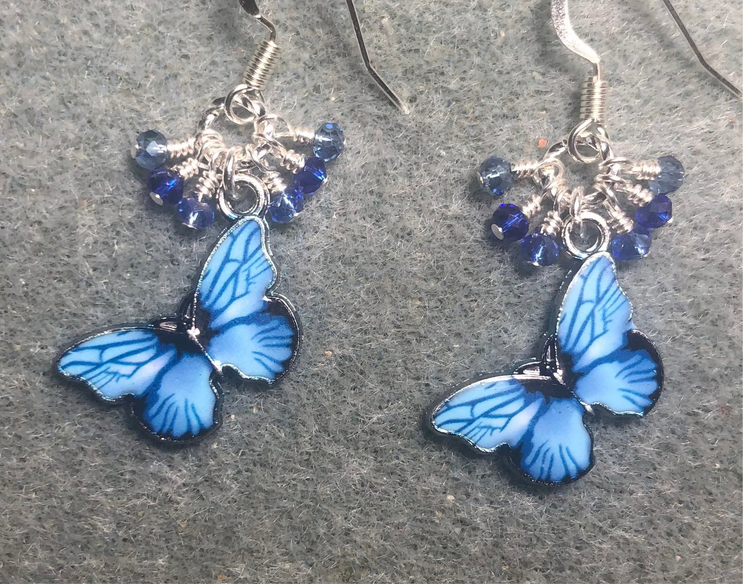 Light blue and dark blue enamel butterfly charm earrings adorned with tiny dangling light blue and dark blue Chinese crystal beads.