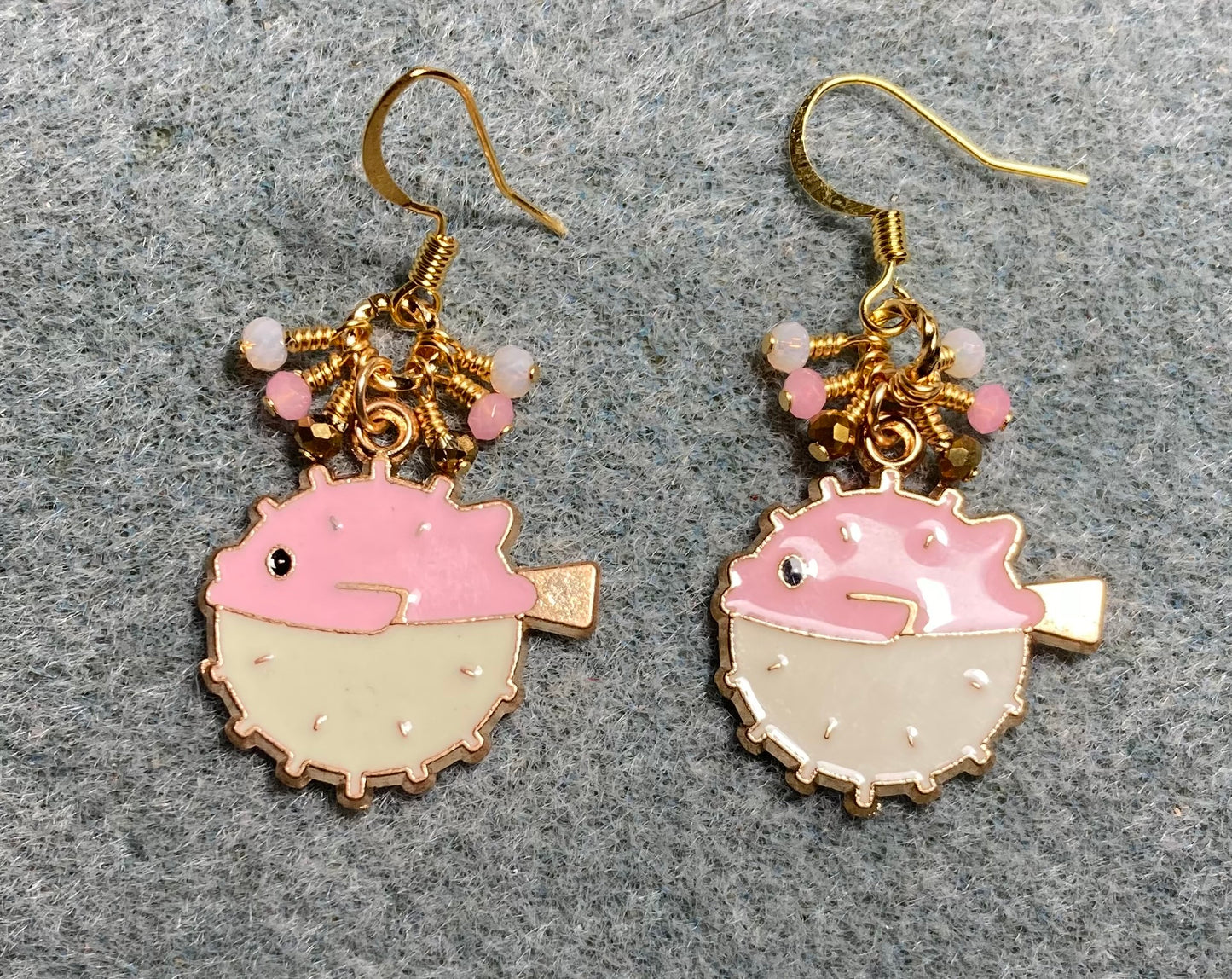 Pink and white enamel pufferfish charm earrings adorned with tiny dangling pink, white, and gold Chinese crystal beads.