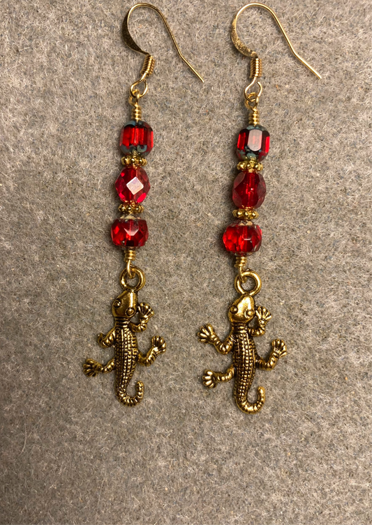 Gold lizard charm earrings adorned with red Czech glass beads.