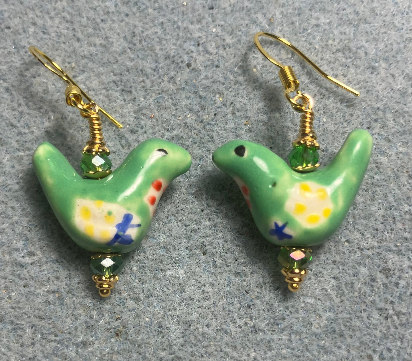 Small green, yellow, and blue ceramic bird bead earrings adorned with green Chinese crystal beads.
