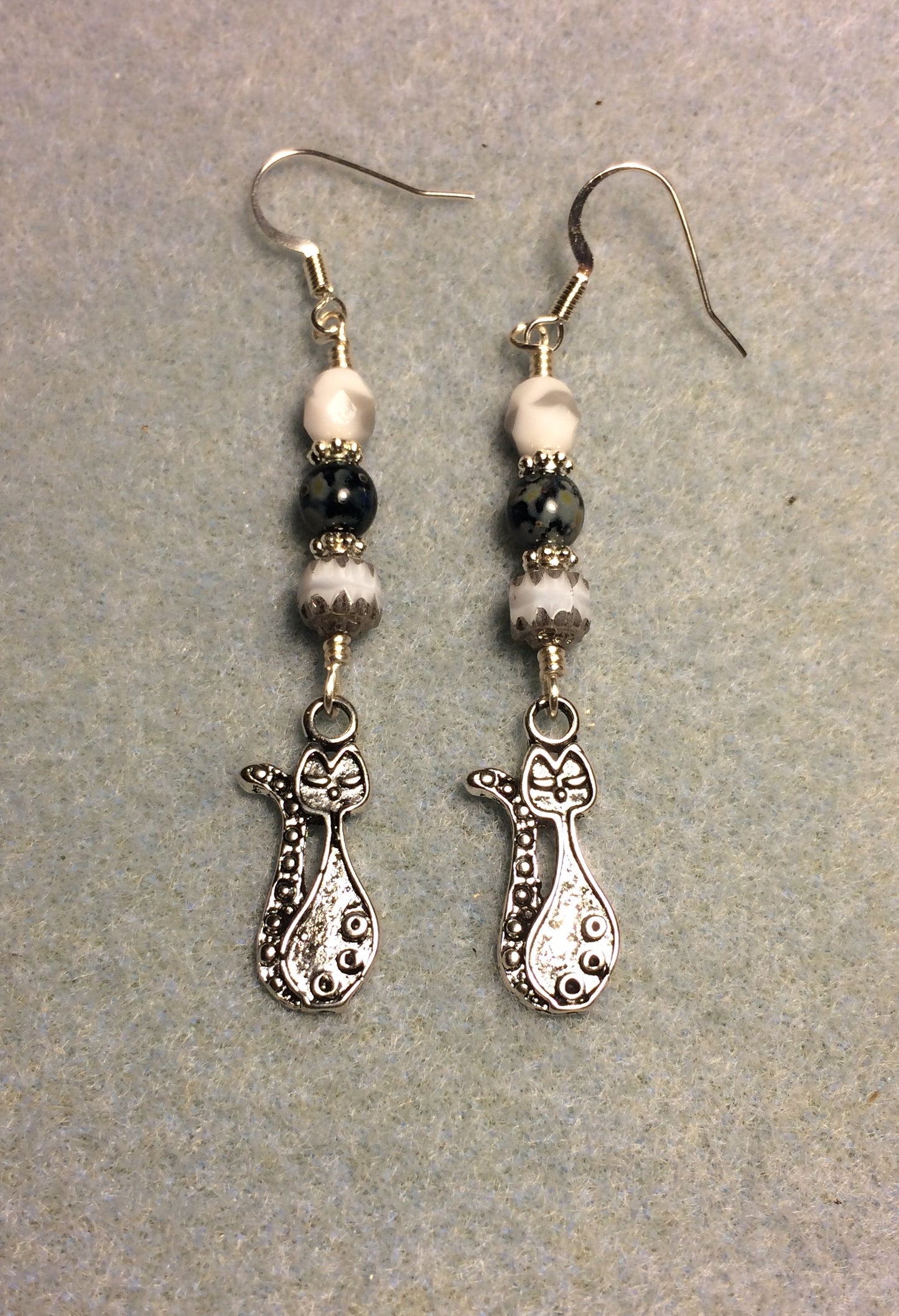 Long silver cat charm earrings adorned with white and black Czech glass beads