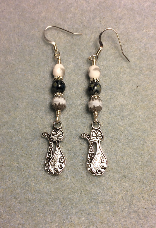 Long silver cat charm earrings adorned with white and black Czech glass beads