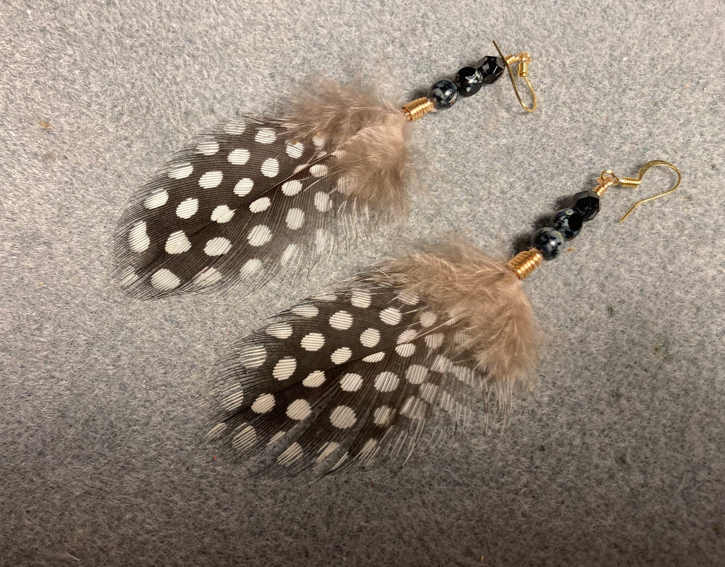 Polka dot guinea hen feather earrings adorned with black Czech glass beads.