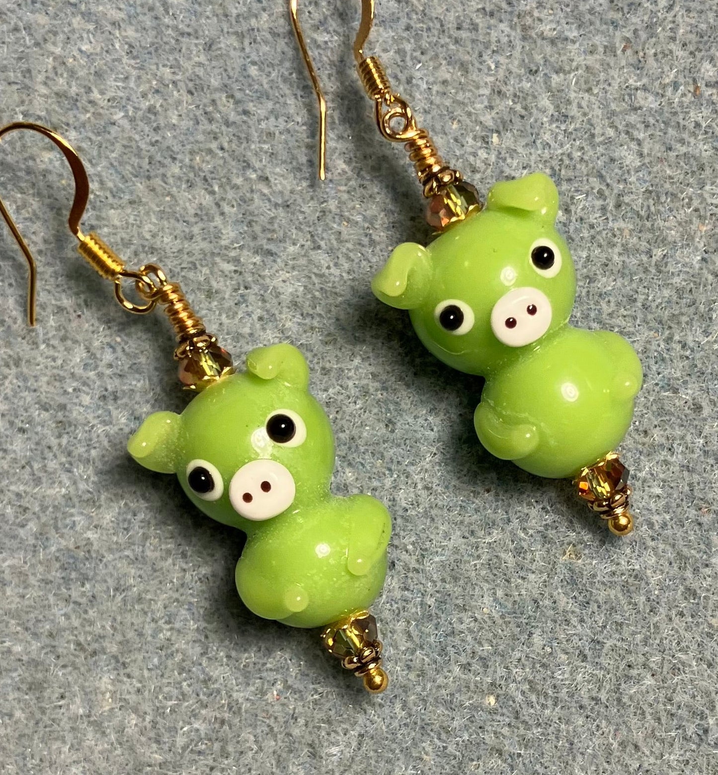 Olive green lamp work standing pig bead earrings adorned with olive green Chinese crystal beads.