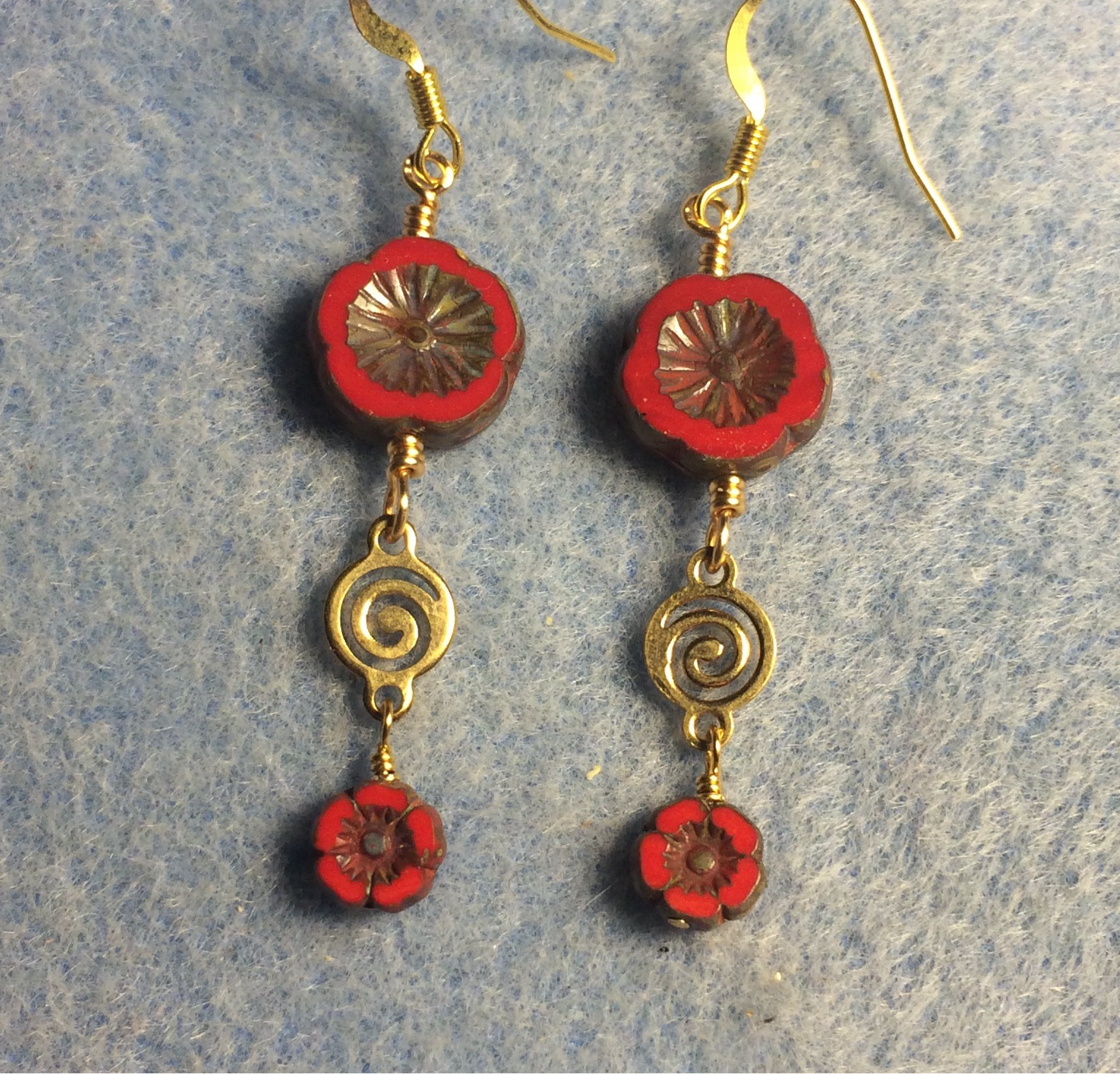 Opaque red Czech glass pansy bead earrings adorned with gold swirly connectors and tiny opaque red Czech glass pansy beads.